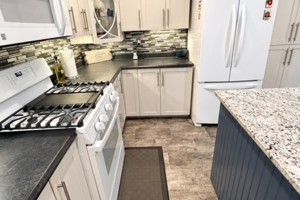 Kitchen view showing a gas stove, white refrigerator, and ample cabinet storage. - 82 Lincoln Road, Grand Falls Windsor