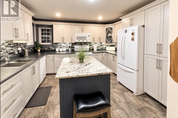 Spacious kitchen featuring light gray cabinets, a granite island, and stainless steel appliances. - 82 Lincoln Road, Grand Falls Windsor