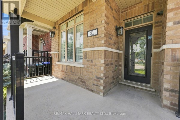 Close-up of the front porch and entrance door of a brick house, showing beige brick and black accents. - 82 Martin Trail, New Tecumseth