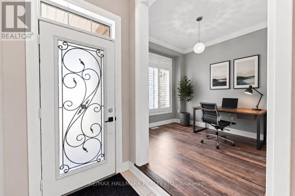 View from the entryway into a room with hardwood floors, grey walls, and plantation shutters on the window. - 82 Martin Trail, New Tecumseth