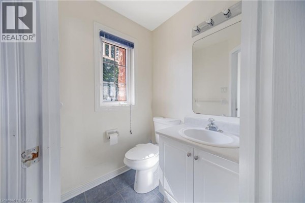Powder room with white vanity, sink, toilet, and blue tiled floor. - 82 Milner Downs Crescent, Ottawa