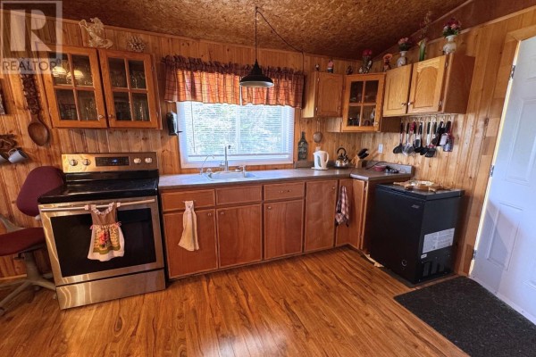 Kitchen with wood-paneled walls, wooden cabinets, a stainless steel stove, and a window. - 82 Mobile First Pond Road, Mobile