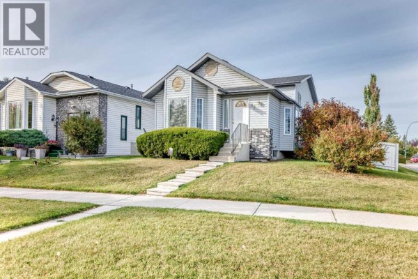 Exterior view of the house and front yard from the sidewalk. - 82 Riverglen Drive Se, Calgary