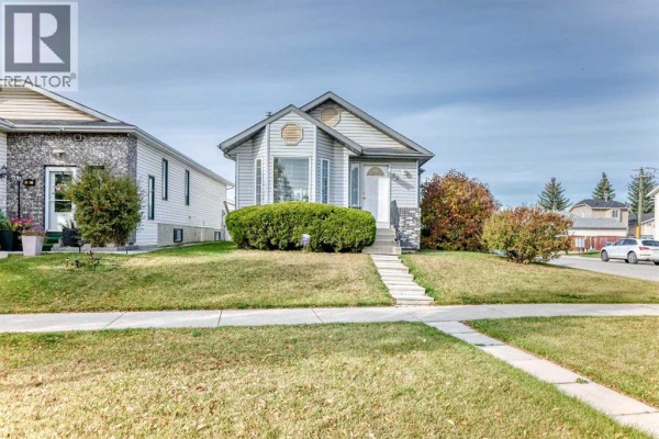 Street view of the house with a concrete sidewalk in the foreground. - 82 Riverglen Drive Se, Calgary