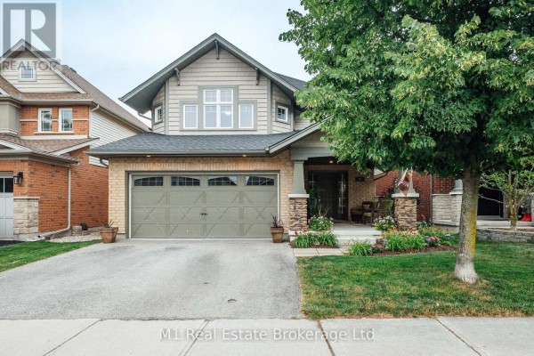 Front exterior of a two-story house with beige brick and grey siding and a large tree. - 82 Vaughan Street, Guelph