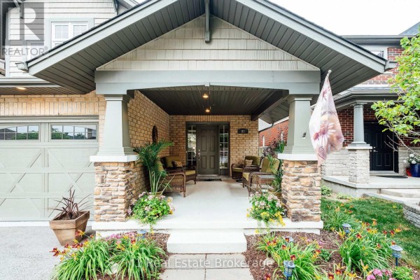 Covered front porch with stone pillars, wicker furniture, and flower planters. - 82 Vaughan Street, Guelph