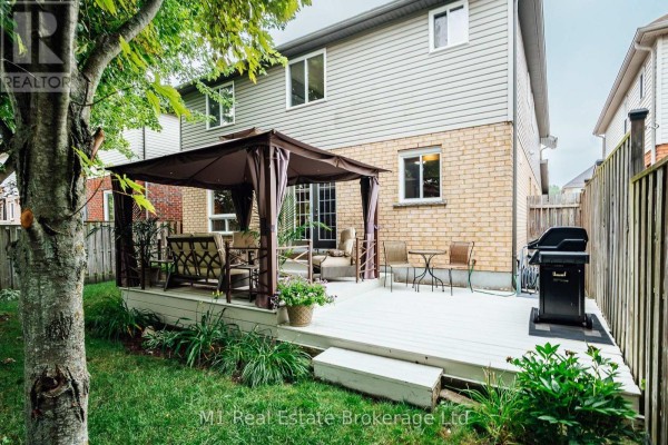 Backyard deck with a gazebo, outdoor furniture, and a grill, surrounded by grass and trees. - 82 Vaughan Street, Guelph