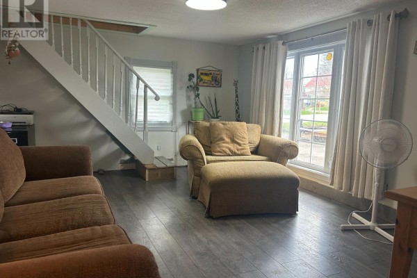 Living room with brown sofas, a recliner, a staircase, and large windows with beige curtains. - 820 Line 11 Line N, Oro Medonte