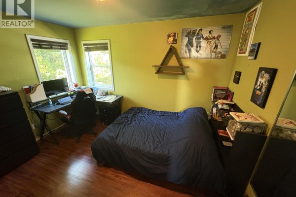 A bedroom with lime green walls, a bed, a desk, and a dresser. - 820 Oceanview Drive, Daajing Giids City