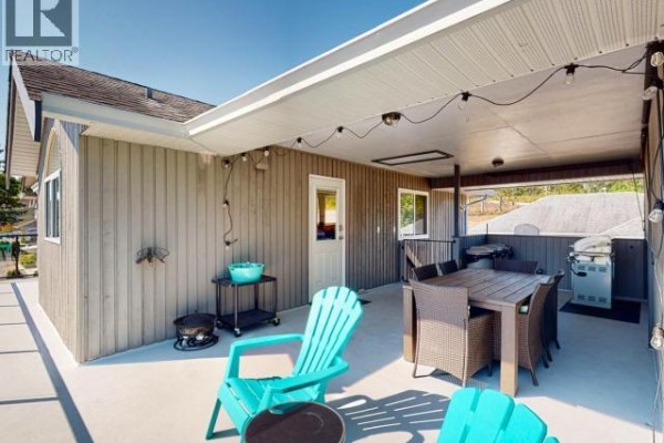 Exterior view of the house showing a patio, stairs, and backyard area. - 8206 Centennial Drive, Powell River