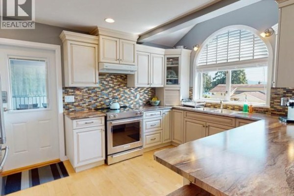 Bright room with hardwood flooring, large window, and workspace area. - 8206 Centennial Drive, Powell River