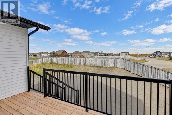 Wooden deck with black metal railings overlooking a fenced backyard and neighborhood houses. - 8209 87a Street, Grande Prairie