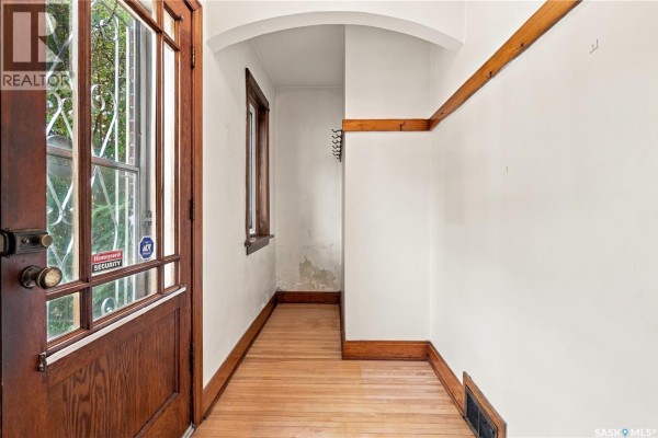 Interior entryway with wood trim, wood floor, and a glass paneled door. - 821 College Avenue, Regina