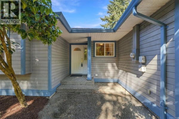 Front entrance area of the house with a walkway, white door, and a window. - 821 Shorewood Dr, Parksville