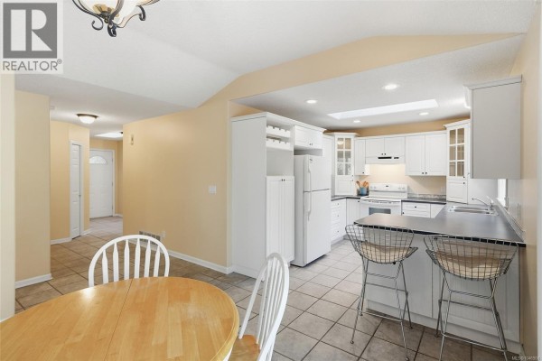 Kitchen and dining area with white cabinets, a breakfast bar with stools, and a round wooden table. - 821 Shorewood Dr, Parksville