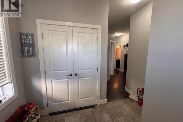 Wooden front steps leading to a wood grain front door with a glass pane on the side of the house. - 8211 96 Avenue, Fort St  John