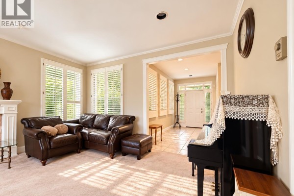 Living room with a sectional sofa, piano, and a view into the entryway with a tiled floor and front door. - 8211 Tugboat Place, Vancouver