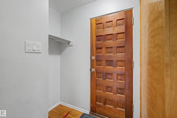 Interior view of the entrance hall with a wooden door and a small closet. - 8215 149 Street Nw, Edmonton