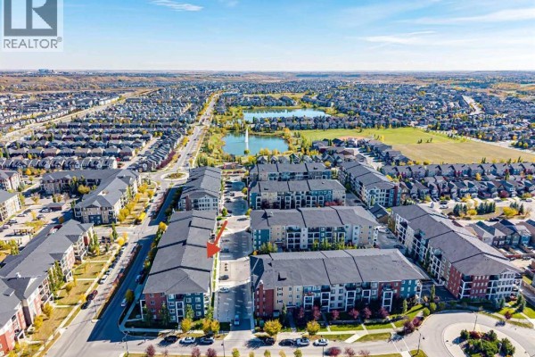 Aerial view of apartment buildings in a suburban neighborhood with a lake and park. - 8216, 151 Legacy Main Street Se, Calgary