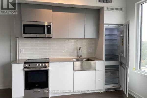 Kitchen with stainless steel appliances, including an open refrigerator, and white and grey cabinets. - 822 - 270 Dufferin Street, Toronto