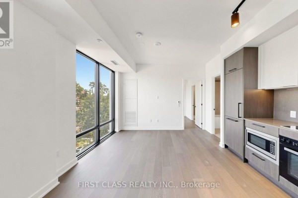 Bedroom with dark wood floors and large windows overlooking adjacent building. - 822 - 91 Montclair Avenue, Toronto