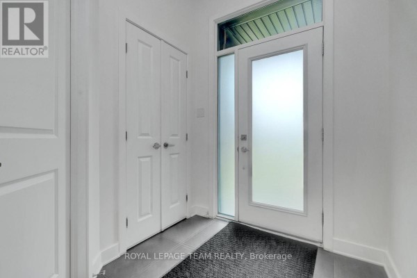 Interior entryway with a frosted glass door, dark grey tiled floor, and a double white door closet. - 822 Chipping Circle, Ottawa