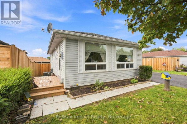 Side exterior of the house with a wooden deck and garden bed. - 822 Southdown Street, Oshawa