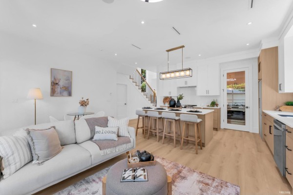 Open-concept living space with a sofa, kitchen island with bar stools, and staircase. - 8221 111b Street, Delta