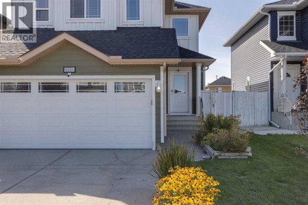 Close-up of the front entrance and garage door of a Calgary home with yellow flowers. - 8226 Saddleridge Drive Ne, Calgary
