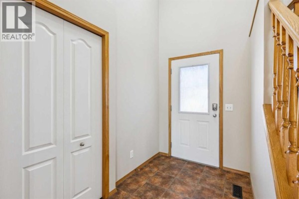 Entranceway of a house with white bi-fold doors, a glass-paned front door, and tiled flooring. - 8226 Saddleridge Drive Ne, Calgary