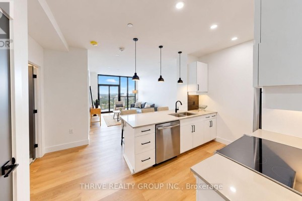 Open concept kitchen and living area with white cabinets and island. - 823 - 100 Fullarton Street, London East