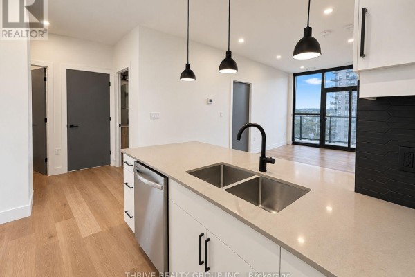 Kitchen island with double sink and faucet, open to living area with view. - 823 - 100 Fullarton Street, London East