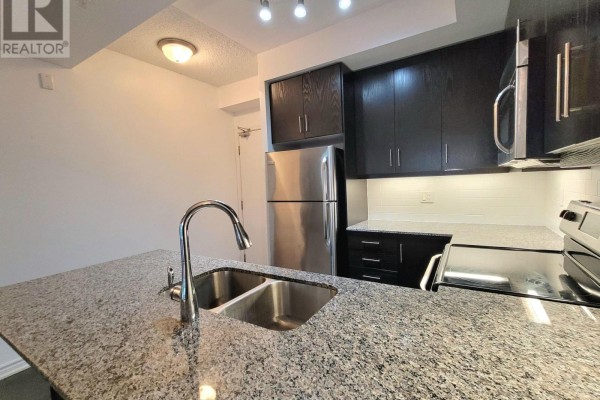 Corner kitchen with dark cabinets, granite island, stainless steel fridge and appliances. - 823 - 15 James Finlay Way, Toronto