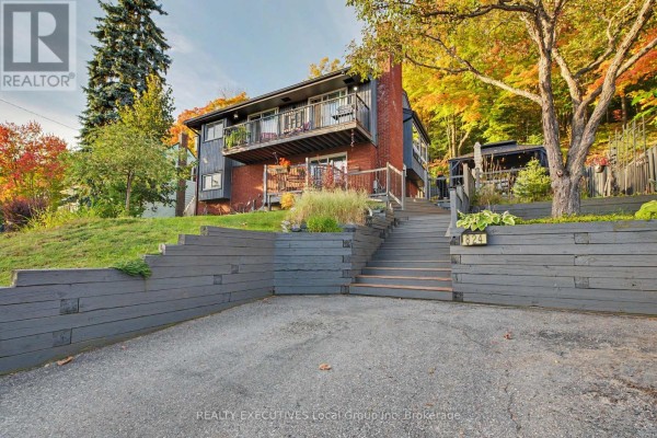 Driveway and front entrance stairs leading up to a red brick and dark wood home. - 824 Ski Club Road, North Bay