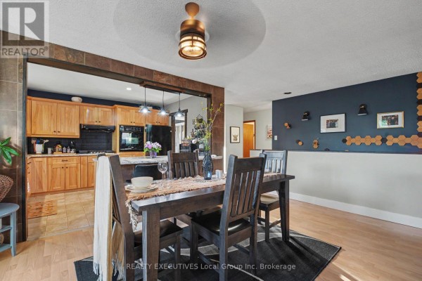 Dining area looking into a kitchen, featuring a dark blue accent wall with hexagonal decor. - 824 Ski Club Road, North Bay