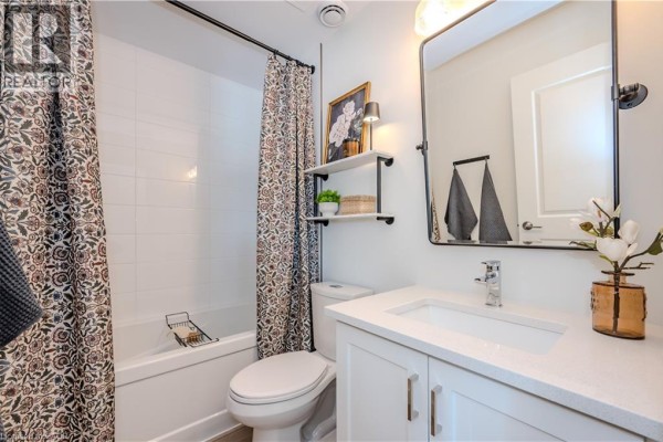 Bathroom with bathtub, toilet, vanity, and mirror. - 824 Woolwich Street Unit# 66, Guelph