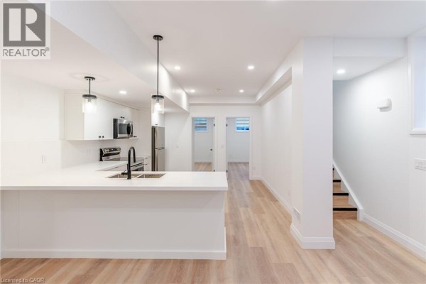 View of the kitchen featuring white cabinets, stainless steel refrigerator, stove, and a large island. - 825 Stirling Avenue S Unit# 4, Kitchener