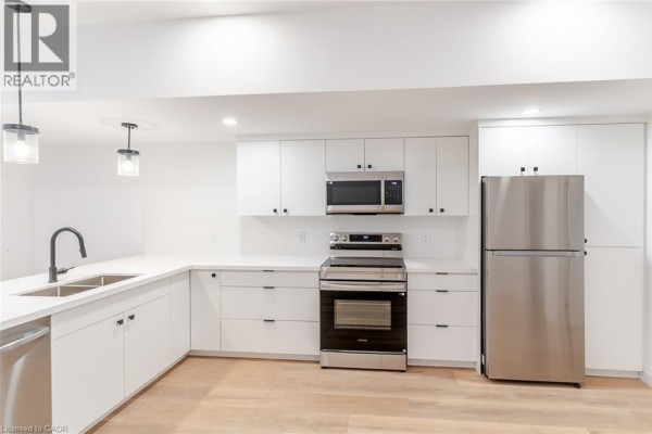Kitchen and dining area with white cabinets, stainless steel appliances, and a breakfast bar. - 825 Stirling Avenue S Unit# 4, Kitchener