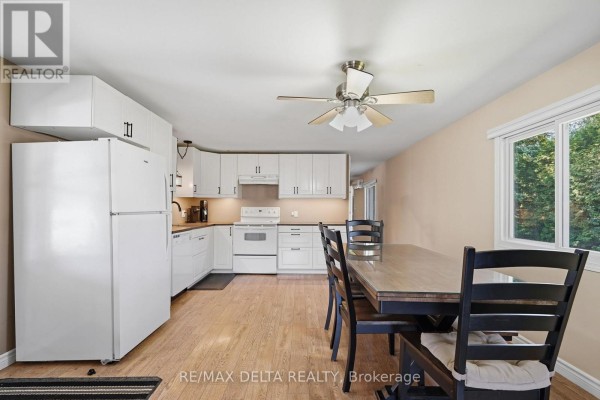 Kitchen and dining area with white cabinets, appliances, wood floors, and a table. - 304 - 8250 County Road 17 Road, Clarence Rockland