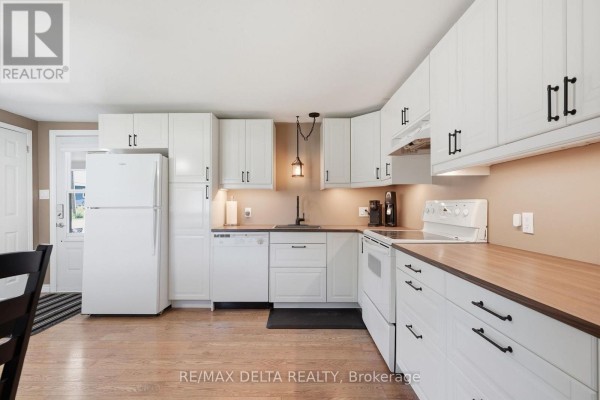 Kitchen area with white cabinets, appliances, and wood countertops overlooking the dining area. - 304 - 8250 County Road 17 Road, Clarence Rockland