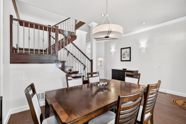 Dining room with a dark wood table, chairs, and a large window overlooking the street. - 8266 211 Street, Langley