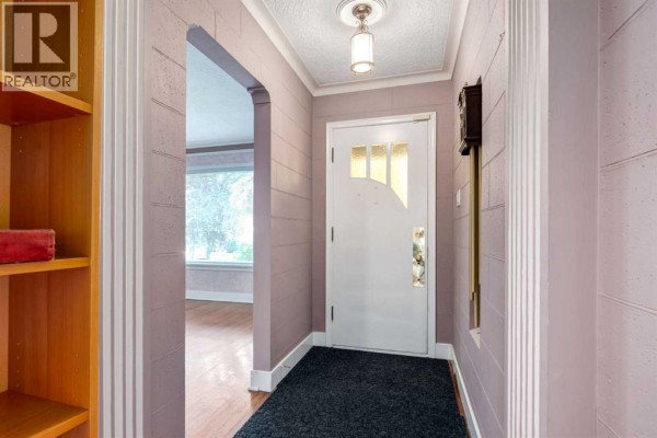 Interior entryway with a white door, black rug, and light purple walls with decorative trim. - 827 17 Avenue Nw, Calgary