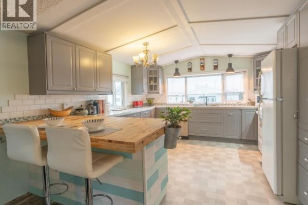 Gray kitchen cabinets with white subway tile backsplash and a butcher block island with bar stools. - 828 Dusseault, Yellowknife