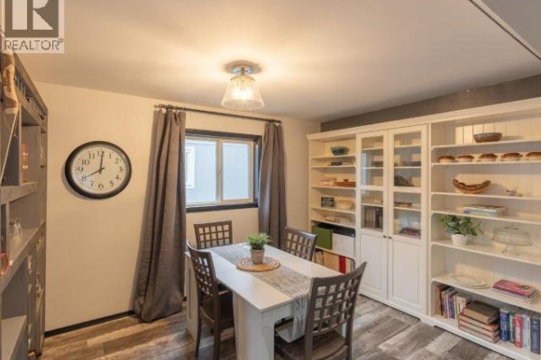 Dining area with a white table and chairs, a large white bookshelf, and a round wall clock. - 828 Dusseault, Yellowknife
