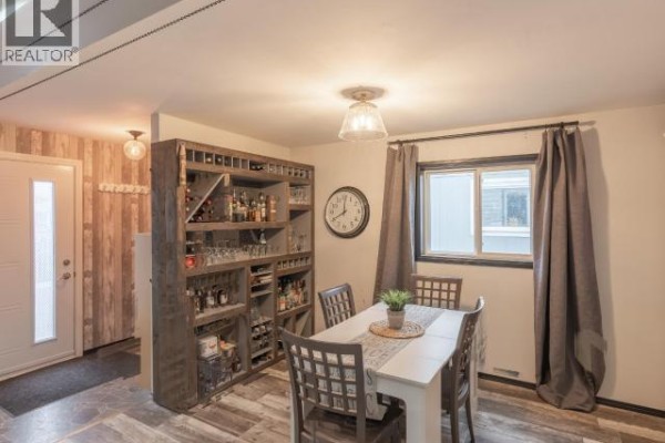 Dining area with a table and chairs, a rustic wine rack, and a view of the front entrance. - 828 Dusseault, Yellowknife