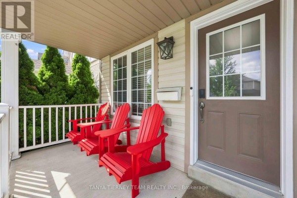 Close-up of the front porch showing a brown door, white trim, and three red chairs. - 828 Taggart Crescent, Oshawa