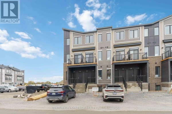 Front view of townhouses with attached garages, stairs, and balconies. Construction materials visible. - 828 Utopie Private, Ottawa