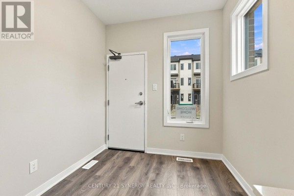 Interior entryway with a white door, dark wood floor, and a window with a view of townhouses. - 828 Utopie Private, Ottawa
