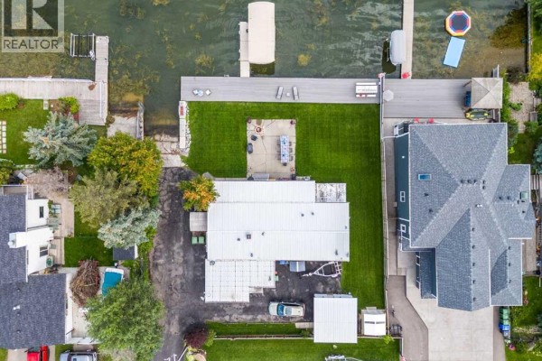 Overhead view of the property with a patio, lawn, and boats docked on the lake. - 828 West Chestermere, Chestermere