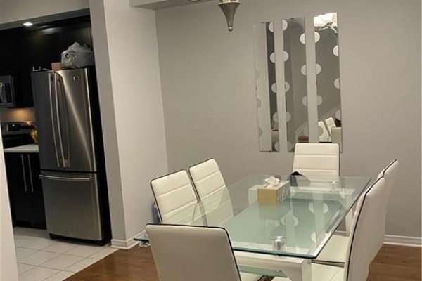 Dining area with a glass-top table, white chairs, and a stainless steel refrigerator. - 829 Percifor Way, Ottawa